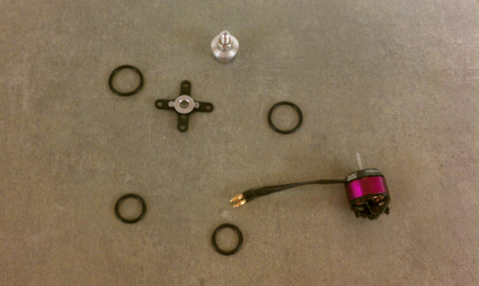Disassembled brushless motor parts. A bell-shaped rotor lined with magnets sits apart from the wound stator.